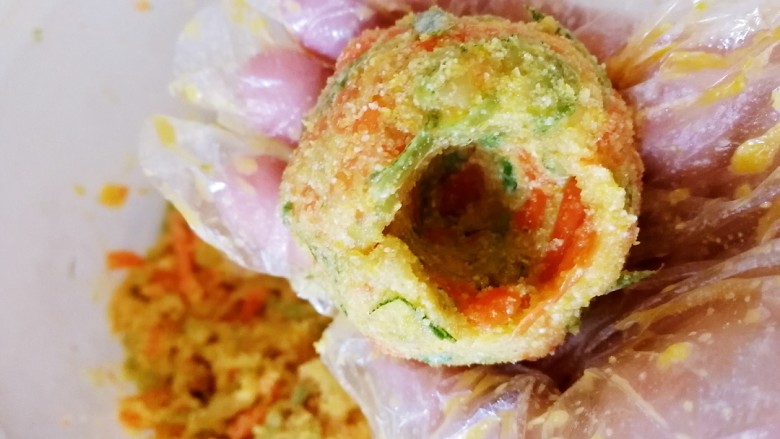 玉米面菜团子,大拇指插入菜团子,其余手指包紧团子并转动。
