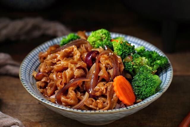 日式肥牛饭,将米饭盛入碗中，摆上西兰花和胡萝卜，上面铺肥牛再淋适量的汤汁。