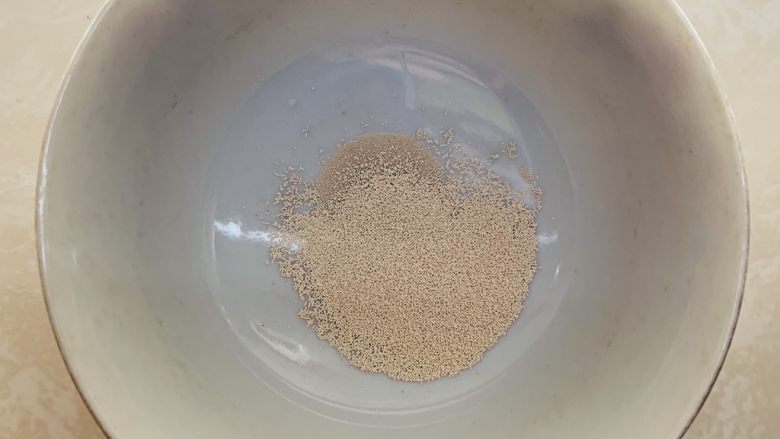 腊肠牛角包,小碗倒入酵母加水静止1分钟。