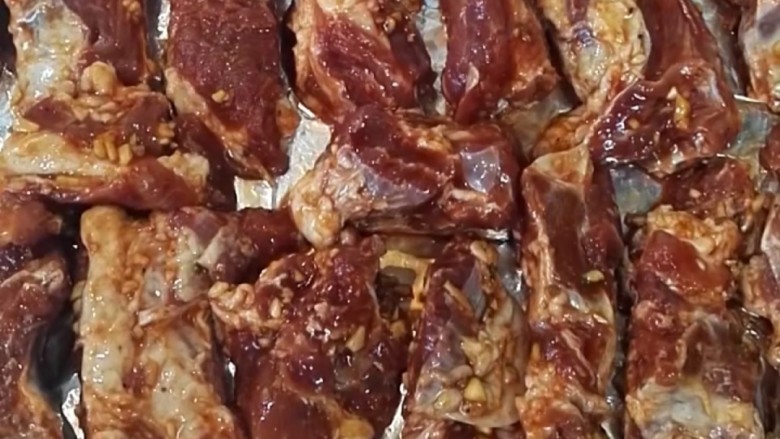 蒜香烤排骨,烤盘上包上锡箔纸,排骨有间隔的依次摆放。
