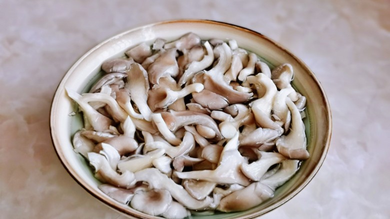 平菇豆腐汤,冲洗干净后放入大口器具中，加入适量盐泡5分钟。