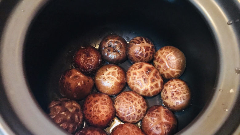 香菇焖鸡,材料都准备好啦,现在开始制作。先在焖锅的底部均匀铺上一层香菇。