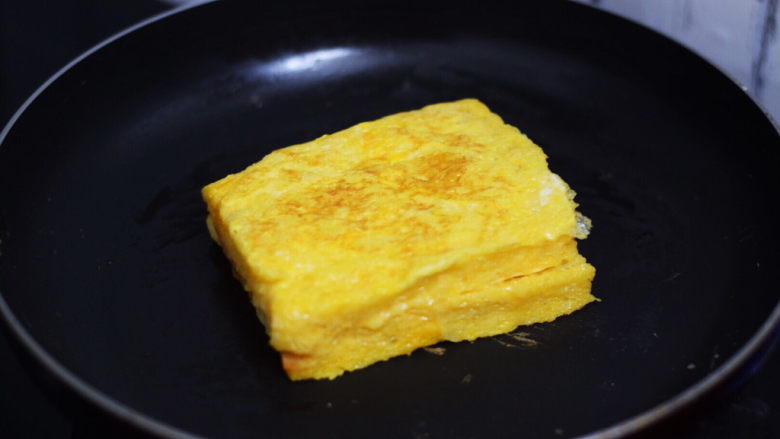 芝士火腿三明治,平底锅刷少许食用油烧热,把沾裹蛋液的吐司放入,小火煎至金黄色