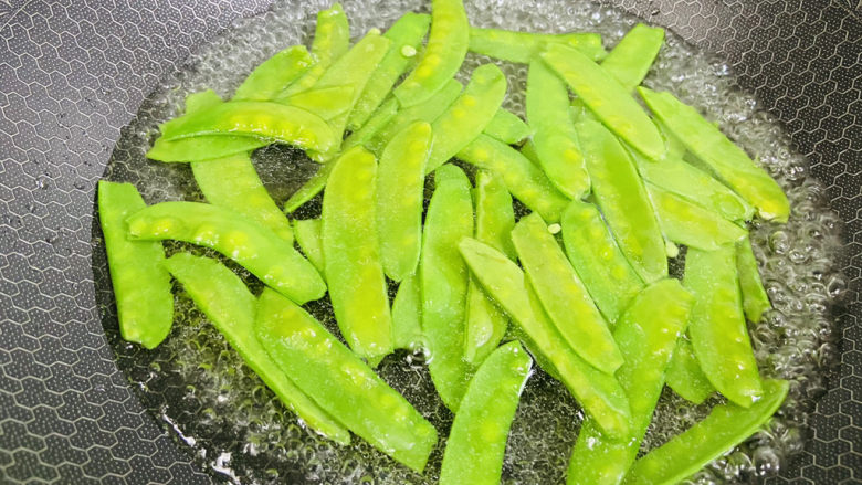 荷兰豆炒香肠,锅里加入清水,加入少许盐和食用油把水烧开后放入荷兰豆焯烫两分钟。荷兰豆焯水的目的是为了让荷兰豆炒出来,效果脆嫩新鲜