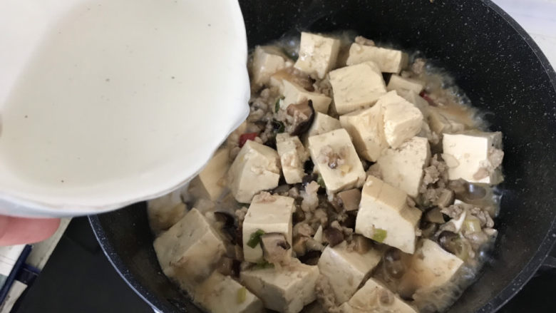 香菇肉末豆腐,豆腐的汤汁收的差不多了,沿着锅边倒入刚才调好的水淀粉;