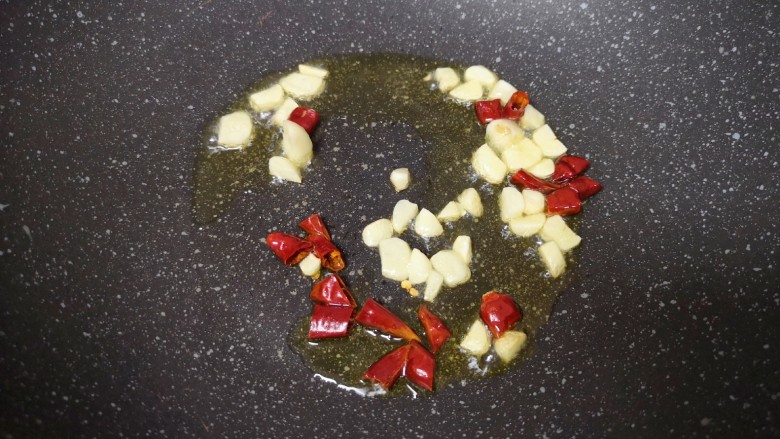醋溜豆芽,炒锅内倒适量的食用油烧热,下入大蒜和干红辣椒炒香。