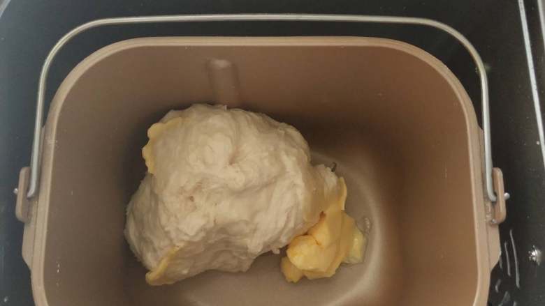 鲜奶蜜豆面包,3,揉成团后加入软化的黄油继续揉。