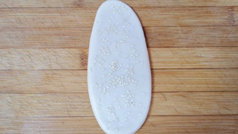 糖火烧,撒上熟白芝麻,用擀面杖轻轻擀一下,让芝麻粘在上面,不容易掉落,一个糖火烧生胚就做好了,依次做完剩下的火烧。