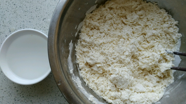 椒盐小花卷,把酵母水全部倒入面粉中,先用筷子搅拌均匀成棉絮状,另外再准备一碗温水。