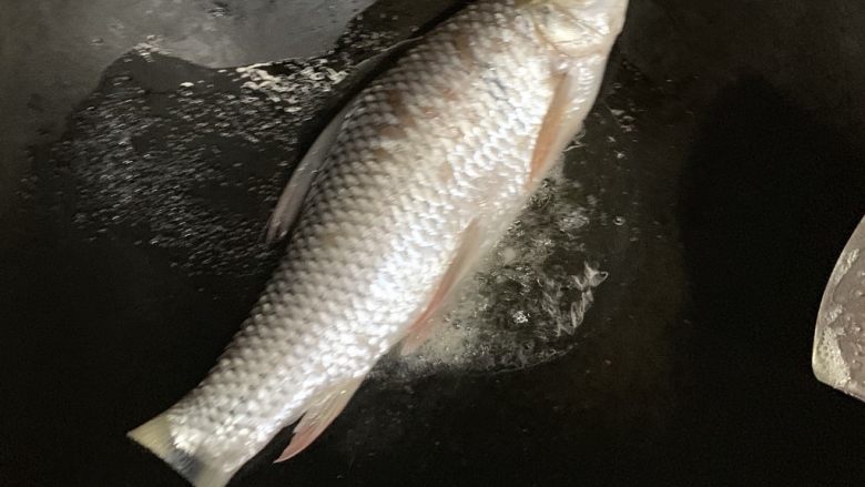 蒜香煎鱼,油冒小泡慢慢放入鱼,鱼身处在锅中心,先让肉厚的地方受热。