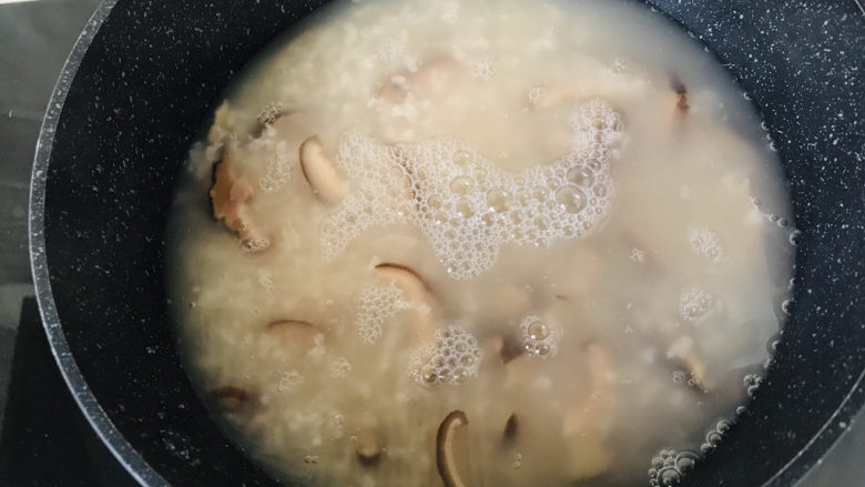 香菇滑鸡粥,第二天清晨伴随香菇白粥的香气醒来,把粥底从电饭锅内胆倒入不粘锅汤锅内小火熬煮;