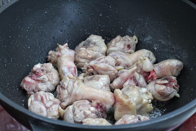 鸡腿炖土豆,锅中倒食用油烧热,放入鸡腿肉翻炒至变色断生状态。