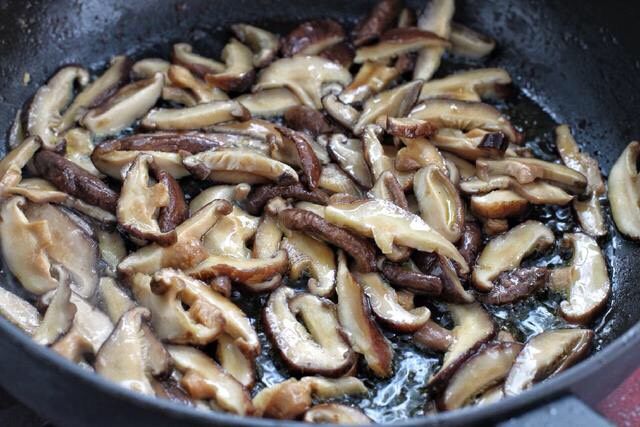 香菇炒肉片,锅中再添适量食用油烧热后,放入香菇炒出香味。