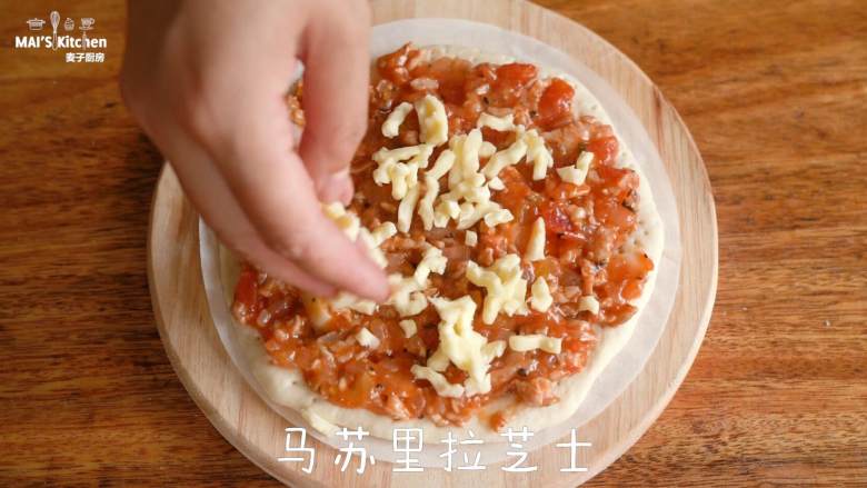 孩子最爱的意大利肉酱披萨,7、取出发酵好的面团,按压排气,分成等量的3等份,取一份置于烘焙纸上,擀成与烘焙纸大小的圆形饼胚,在饼胚上扎上小孔,抹上番茄肉酱,撒上马苏里拉芝士。