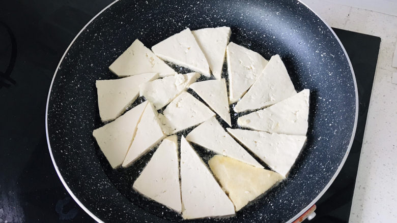 青椒炒豆腐,煎锅里倒油,中小火煎豆腐;