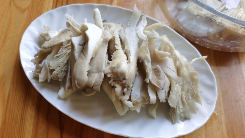 平菇炒鸡蛋,攥去平菇里吸收的水分,用手撕成条状。