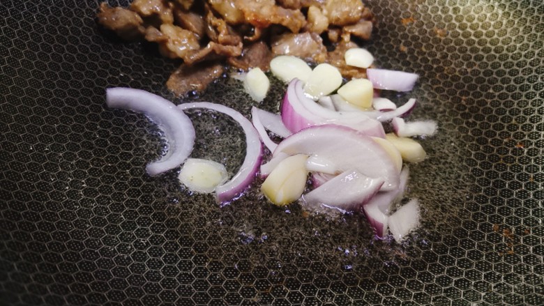 香菇炒肉片,将炒好的肉片推在锅边,用锅中底油爆香蒜片和洋葱丝