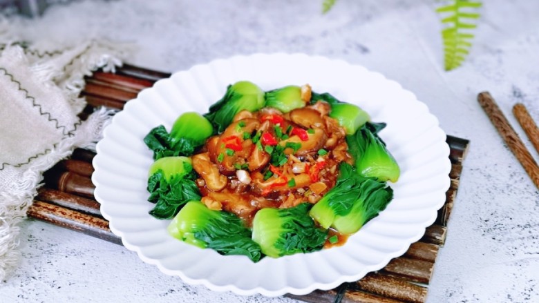 香菇炒青菜,把菜心摆盘,炒熟的香菇盛盘子中间,撒上葱花和红椒点缀。