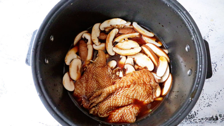 电饭煲鸡腿焖饭,将大米放入电饭煲,先倒入腌制鸡腿的酱汁,再加入水,总共水量就跟平时煮饭一样多,再加入香菇,放入鸡腿,皮朝上