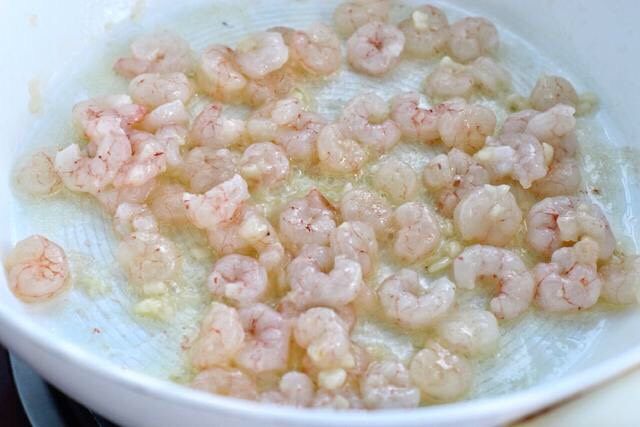 秋葵炒虾仁,锅中倒适量食用油烧至五成热,先放入蒜末小火炒出香味,接着放入浆好的虾仁炒至变色。