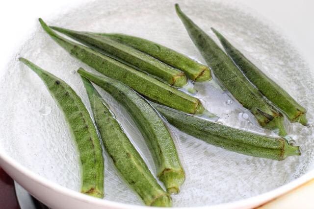 秋葵炒虾仁,锅中烧开水放入洗净的秋葵,再加入少许盐和几滴食用油,将秋葵焯烫一分钟左右,待秋葵颜色变得更绿后捞出过凉水。