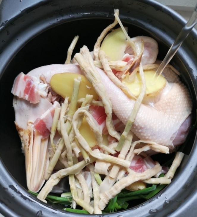 老鸭煲,鸭肉放到砂锅中,笋干,咸肉,姜,葱,一起放进砂锅,加水,水要多一点,最好把鸭子全部浸泡在水中。