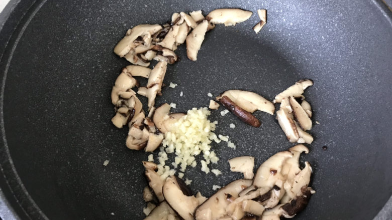 香菇炒青菜,炒至香菇片变软,加入蒜末炒香;