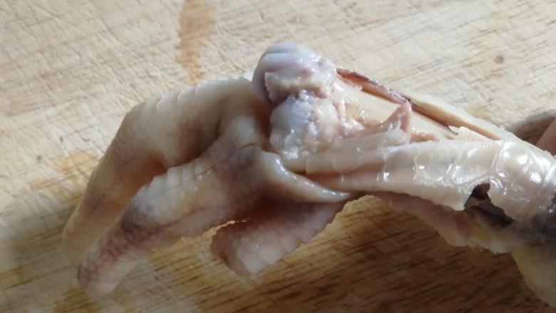 无骨鸡爪,在关节处左右摇向下掰,漏出骨头,用刀划去骨头两边肉,底部切一刀,保留脆骨。