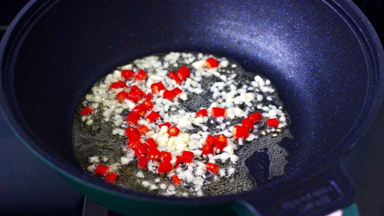 辣爆鸡丁秋葵,锅中倒入花生油烧热后,爆香小米辣和大蒜。