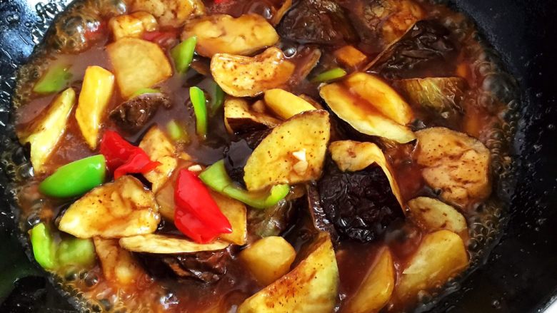 烧茄子,倒入炸好的茄子块、土豆片和剩下的蒜末炒匀,食材都裹上汤汁后关火。