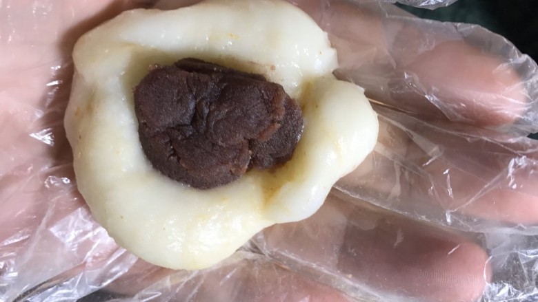 红豆糯米糍,放冷后开始制作,把糯米分成等量剂子,捏成饼状,放入红豆沙