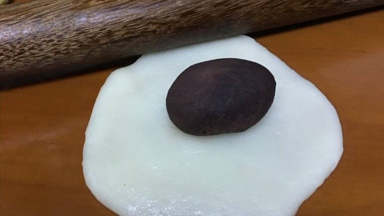 红豆糯米糍,用擀面杖将团子压成皮,放入红豆沙馅,再将其捏圆