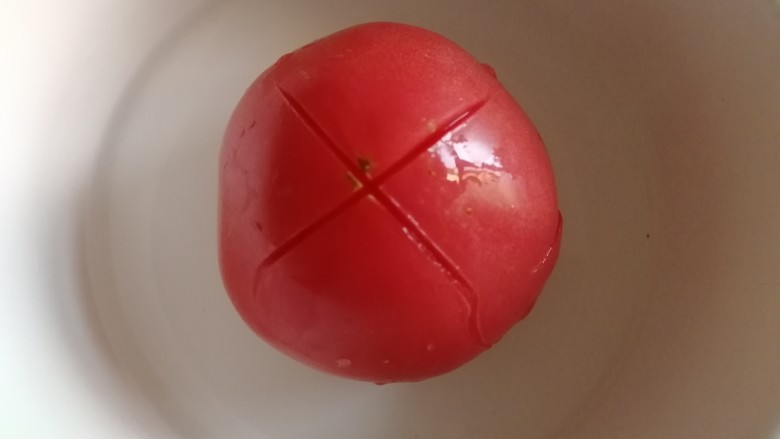 番茄土豆片,番茄顶部切花刀,在开水滚几圈。