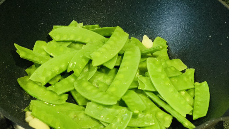 荷兰豆炒虾仁,锅里加蒜瓣炒香,倒入荷兰豆