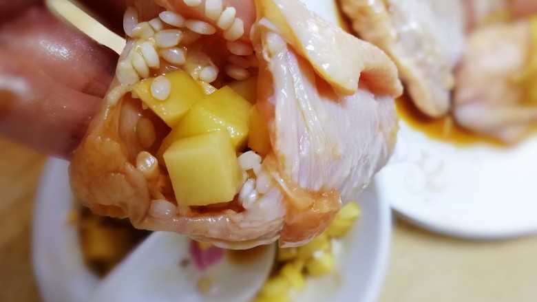 糯米蒸鸡翅,用勺子把混有糯米的土豆块塞进翅中里,填满。