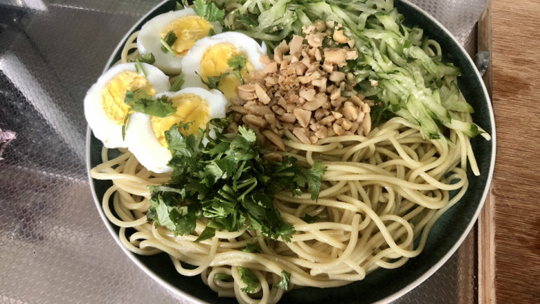 麻酱凉面,把面条沥水捞出装盘,摆上黄瓜丝花生碎,煮鸡蛋,香菜碎