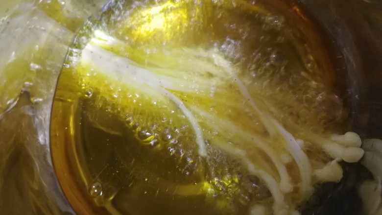 油炸金针菇,锅里倒入适量油,中小火油温五成热,放入金针菇慢炸。