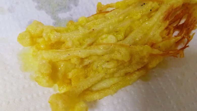 油炸金针菇,炸至外壳酥脆就夹出,放在厨房纸上吸油。