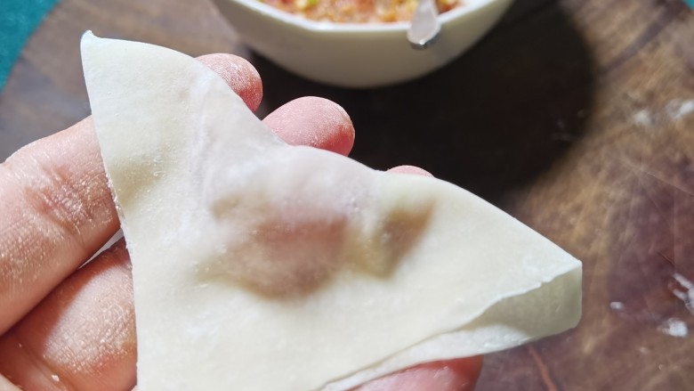 三鲜小馄饨,将馄饨皮对角折过来成三角形,用手把周围捏紧。
