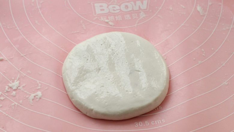 紫薯芝麻饼,用双手揉搓滚圆,然后放到操作台上,再轻轻按压成薄厚适中的饼状。
