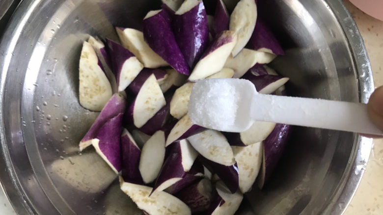 毛豆烧茄子,加入一勺盐,抓拌均匀腌制10分钟