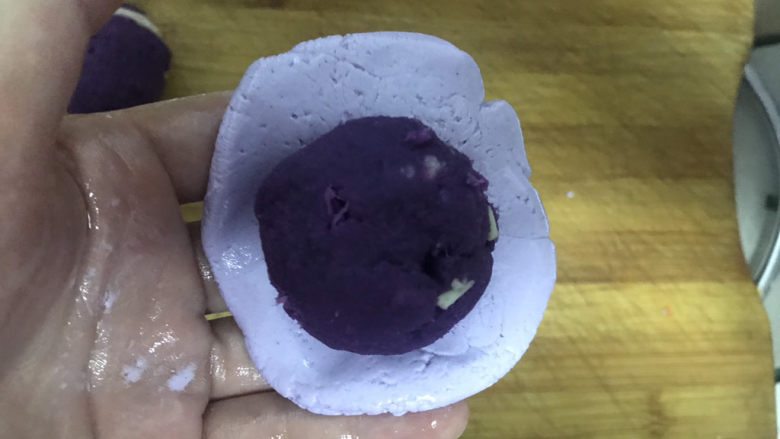 紫薯芝麻饼,取一个小剂子,用手压成圆形饼状包入紫薯球