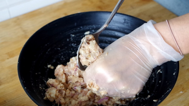 莲藕肉丸,左手取适量肉馅,在虎口处挤出肉丸子,右手用小勺将肉丸子取下,大小尽量均匀一些。