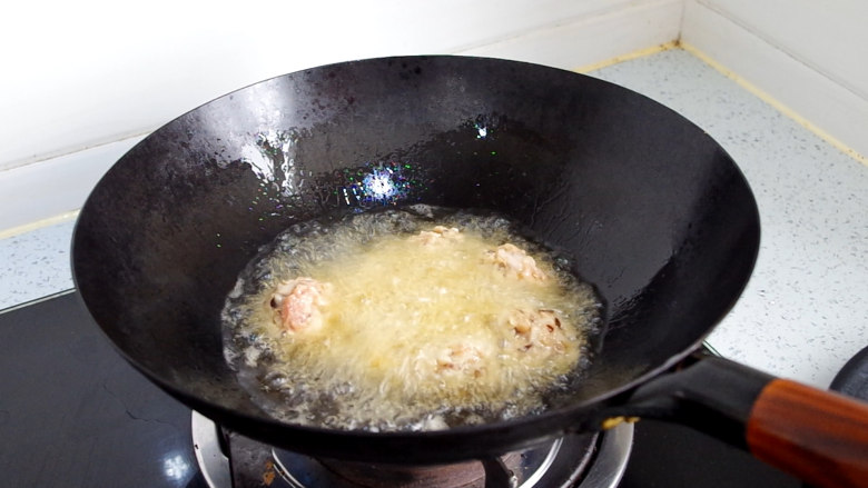莲藕肉丸,油锅里倒入适量食用油,待油温7成时,放入丸子,用中火炸制,丸子刚放入锅中先不要搅动,等丸子在油锅中定型后,用筷子顺着一个方向慢慢搅动。