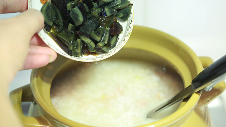 猪肝瘦肉粥,倒进瘦肉和皮蛋转大火烧开再转小火,保持多搅拌;