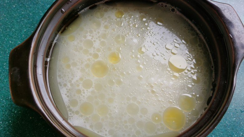 豉汁排骨煲仔饭,砂锅底部及四周抹上一层油,放入泡好的大米,加入水,水要莫过大米约1厘米左右。