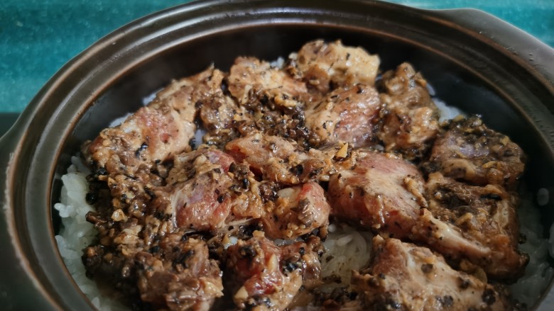 豉汁排骨煲仔饭,围着锅边淋上少许油,再放入排骨,盖上盖子继续煮约8—10分钟。这时可以转动砂锅,让烧锅底部受热均匀,烧出金黄焦脆的锅巴。
