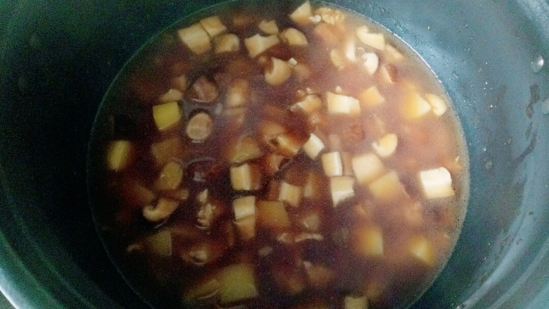 香菇滑鸡煲仔饭,将煮开的菜倒入电饭锅中,汤汁和平时煮米饭的一样就可以了