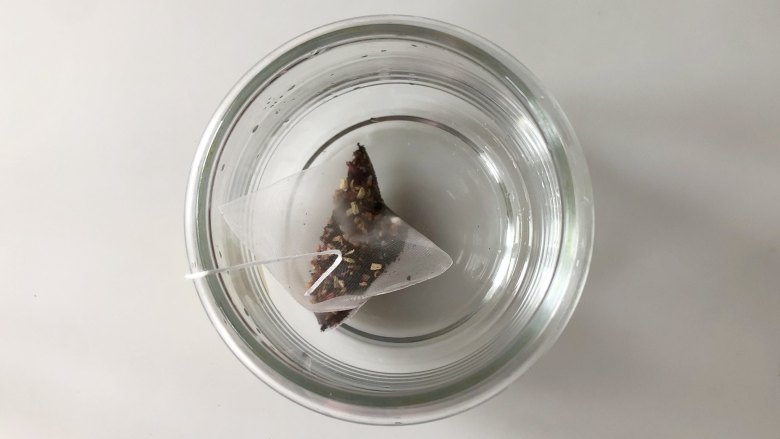 网红水果串串茶,自己在家做,好看又好吃,因为天气还比较热,做凉的水果茶比较清爽,要等茶凉了再加进水果,所以先把茶泡上,把玫瑰茄红茶包放入玻璃杯;