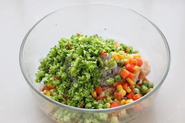 鲜虾玉米饼,将西兰花挤干多余水分切碎,同冷冻蔬菜一起放到鸡肉糜中。